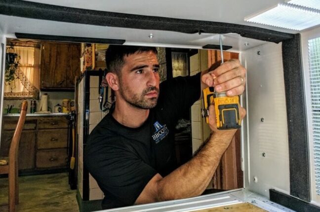 A window AC technician installing